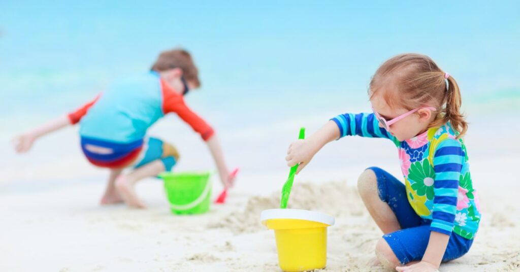 Børn som leger med sandlegetøj ved stranden